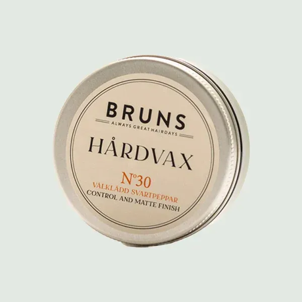 Een rond, zilverkleurig blikje met Bruns No. 30 Hårdvax haarproduct, voorzien van een crèmekleurig etiket op een lichtgroene achtergrond.