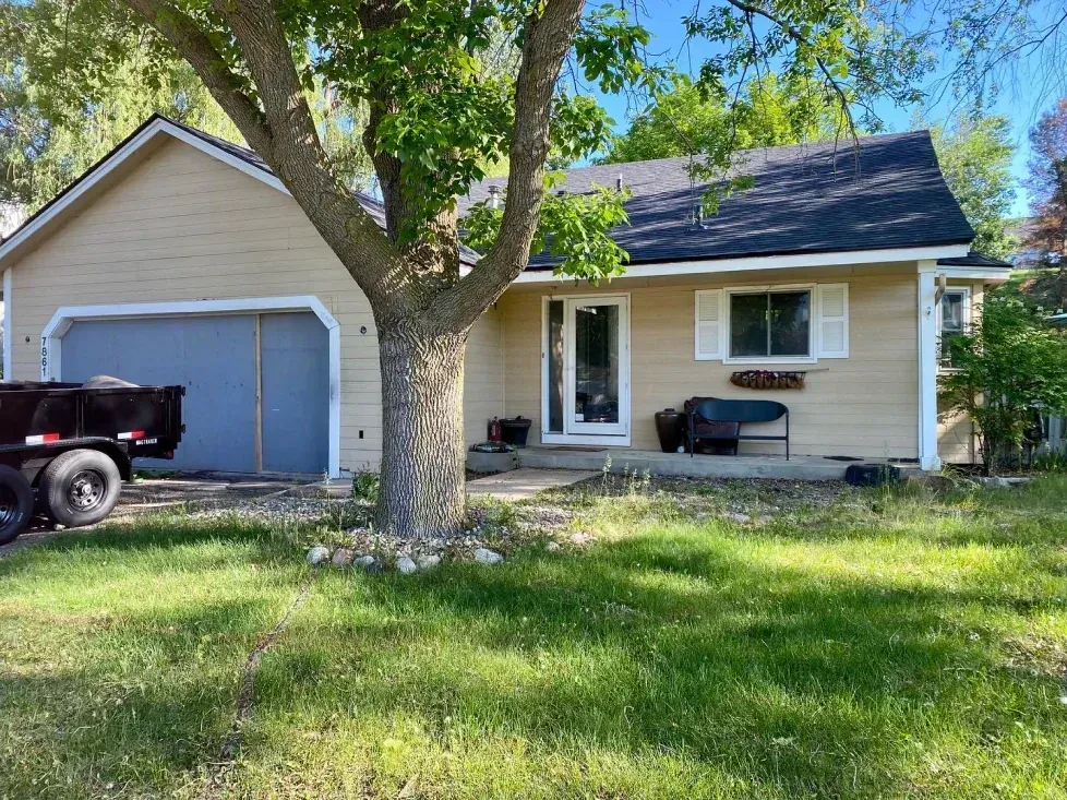 A one-story house with a tan exterior and a dark gray roof. 