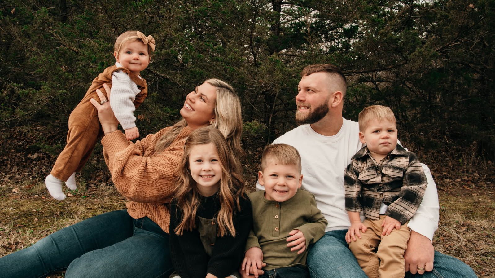 Stone retaining wall with steps leading to a yellow house. Reddish-brown mulch covers the foreground