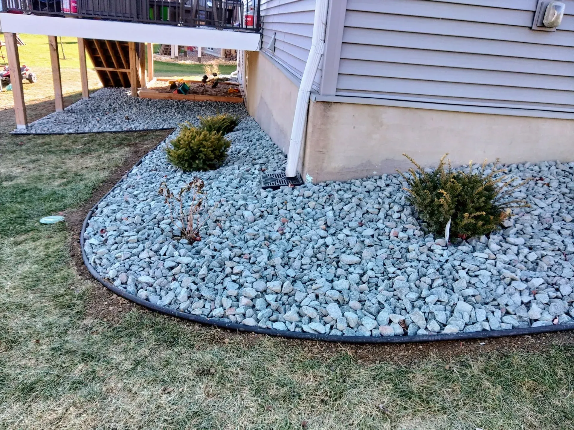 Landscaped yard bed with bluish-gray river rock,