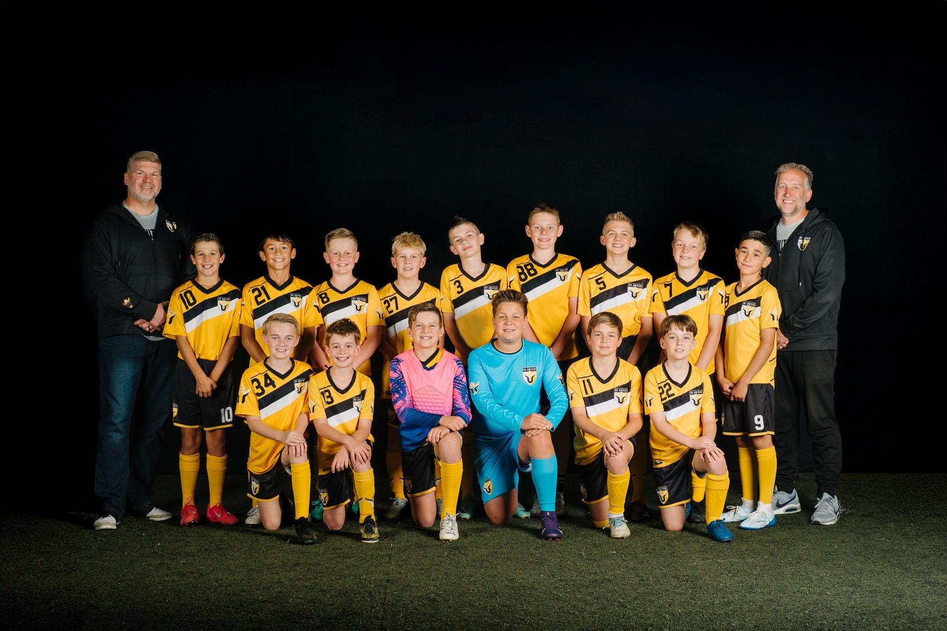 Baseball glove with ball on green grass, with blurred baseballs in the background.