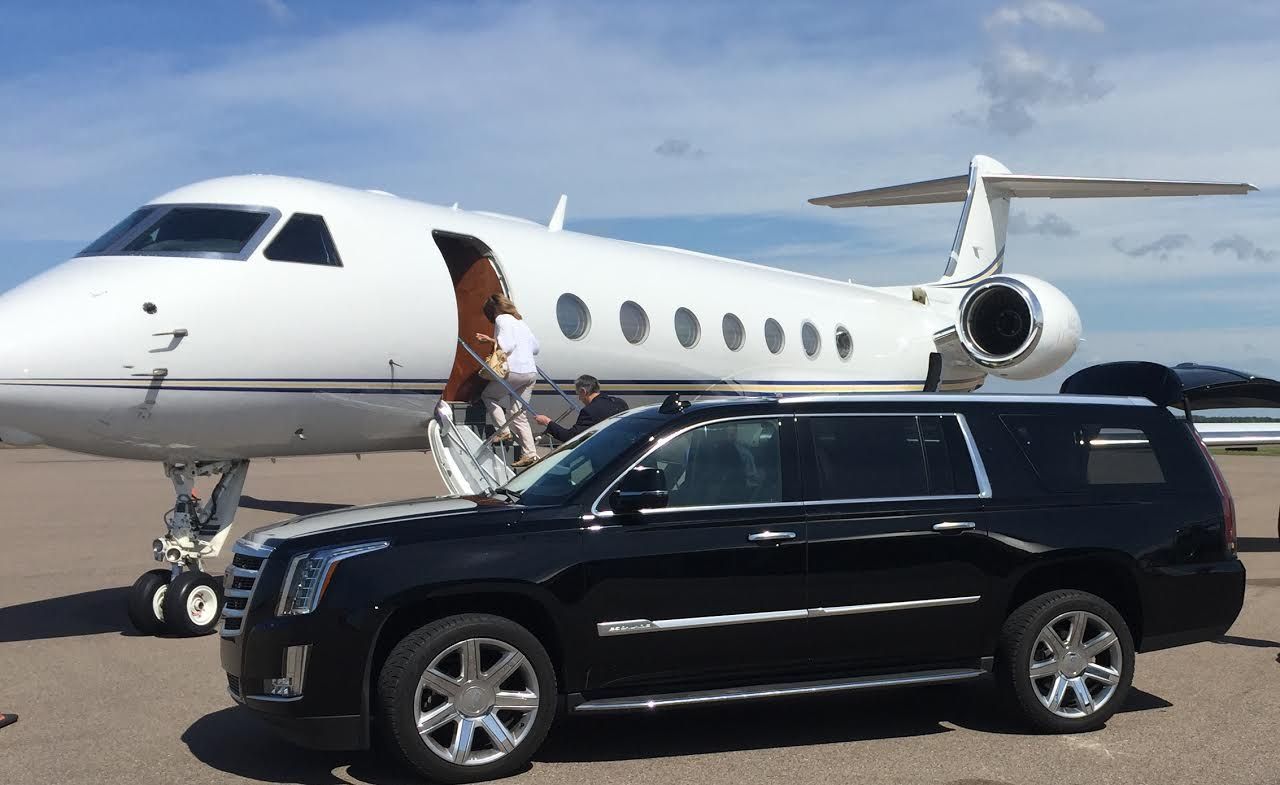 A black suv is parked in front of a private jet