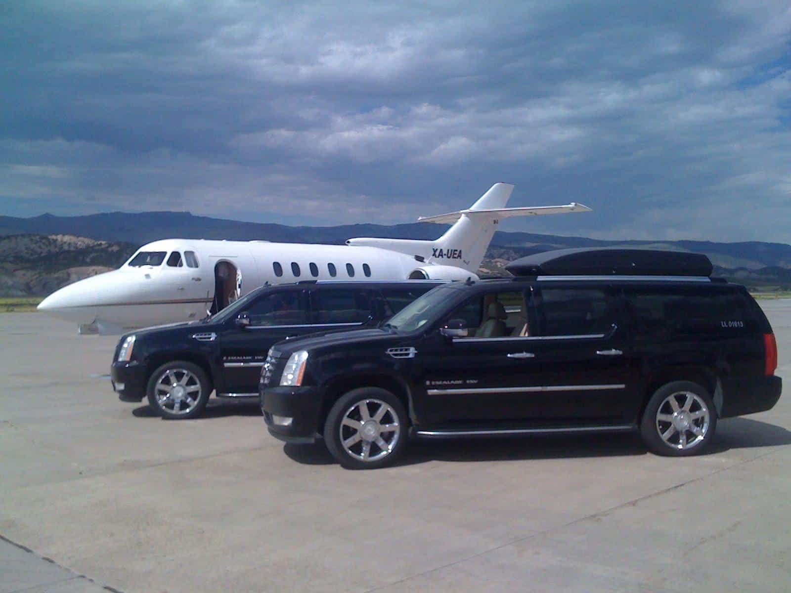 Two cars are parked in front of a private jet