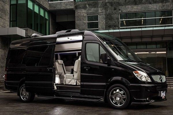 A black van is parked in front of a building with its doors open.