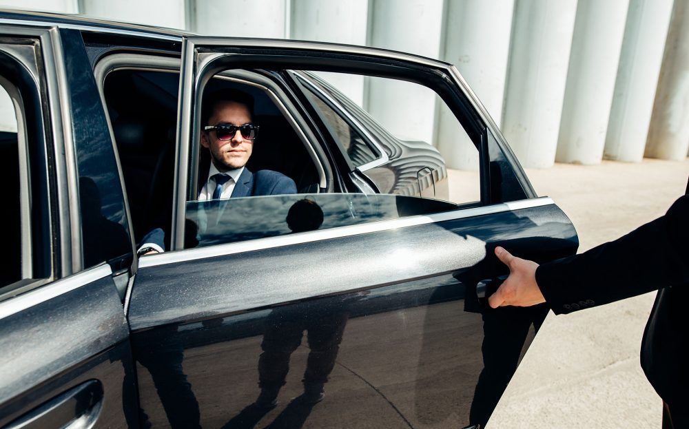 A man in a suit is getting out of a limousine.
