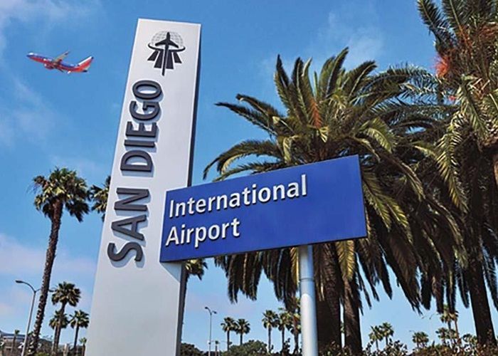 A plane is flying over a sign for the san diego international airport
