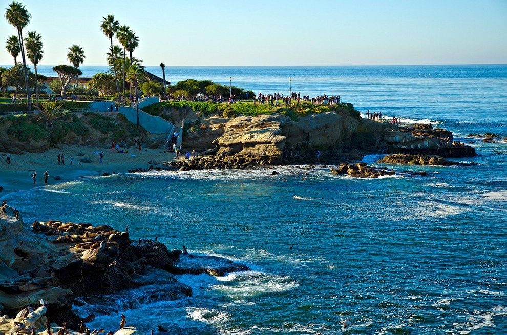A group of people are standing on a rocky cliff overlooking the ocean.
