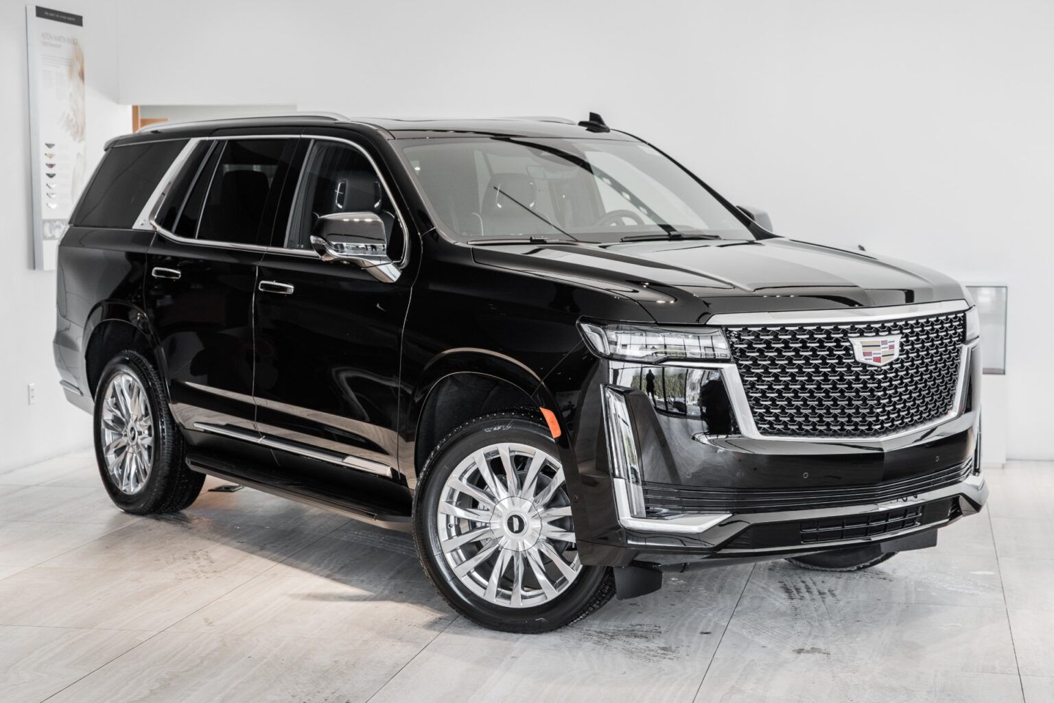 A black cadillac escalade is parked in a showroom.