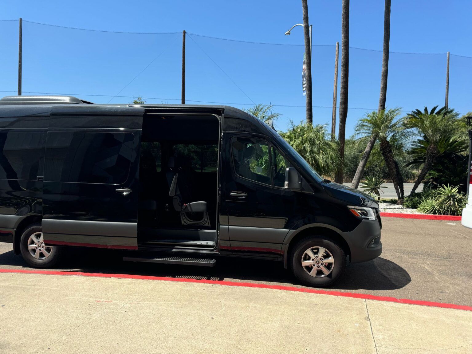 A black van is parked in a parking lot with the door open.
