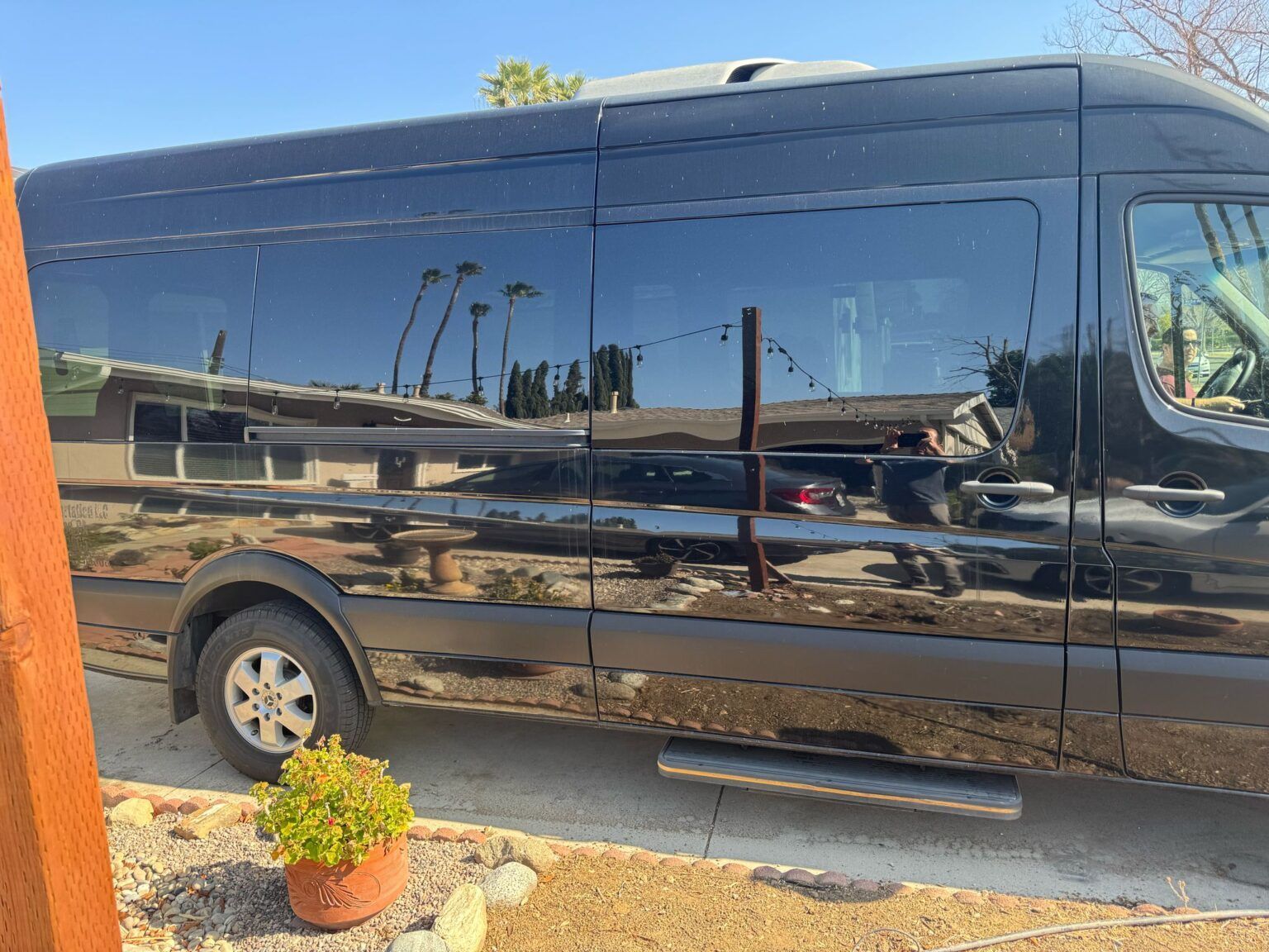 A black van is parked in a driveway next to a house.