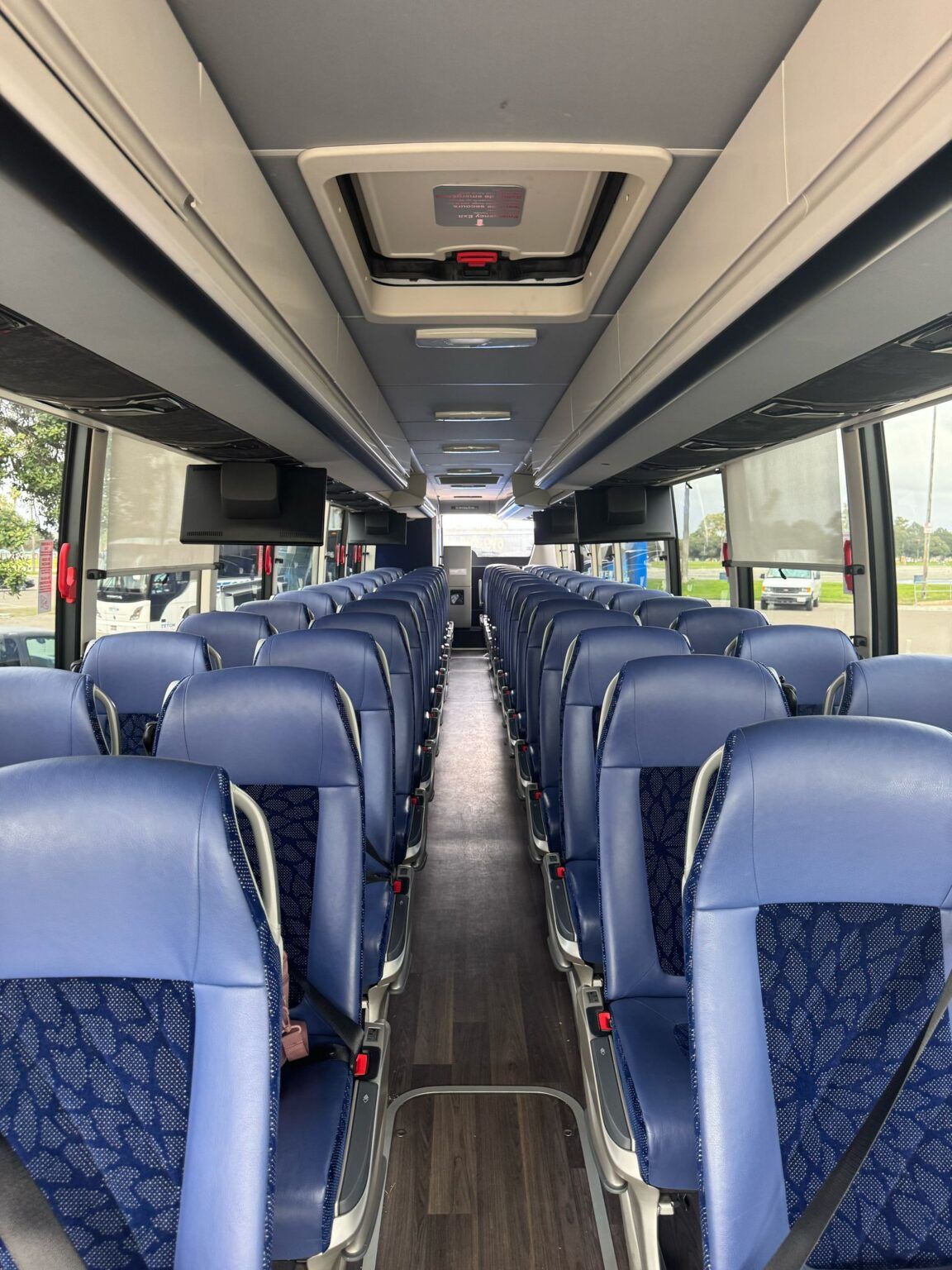 The inside of a bus with blue seats and a ceiling fan.