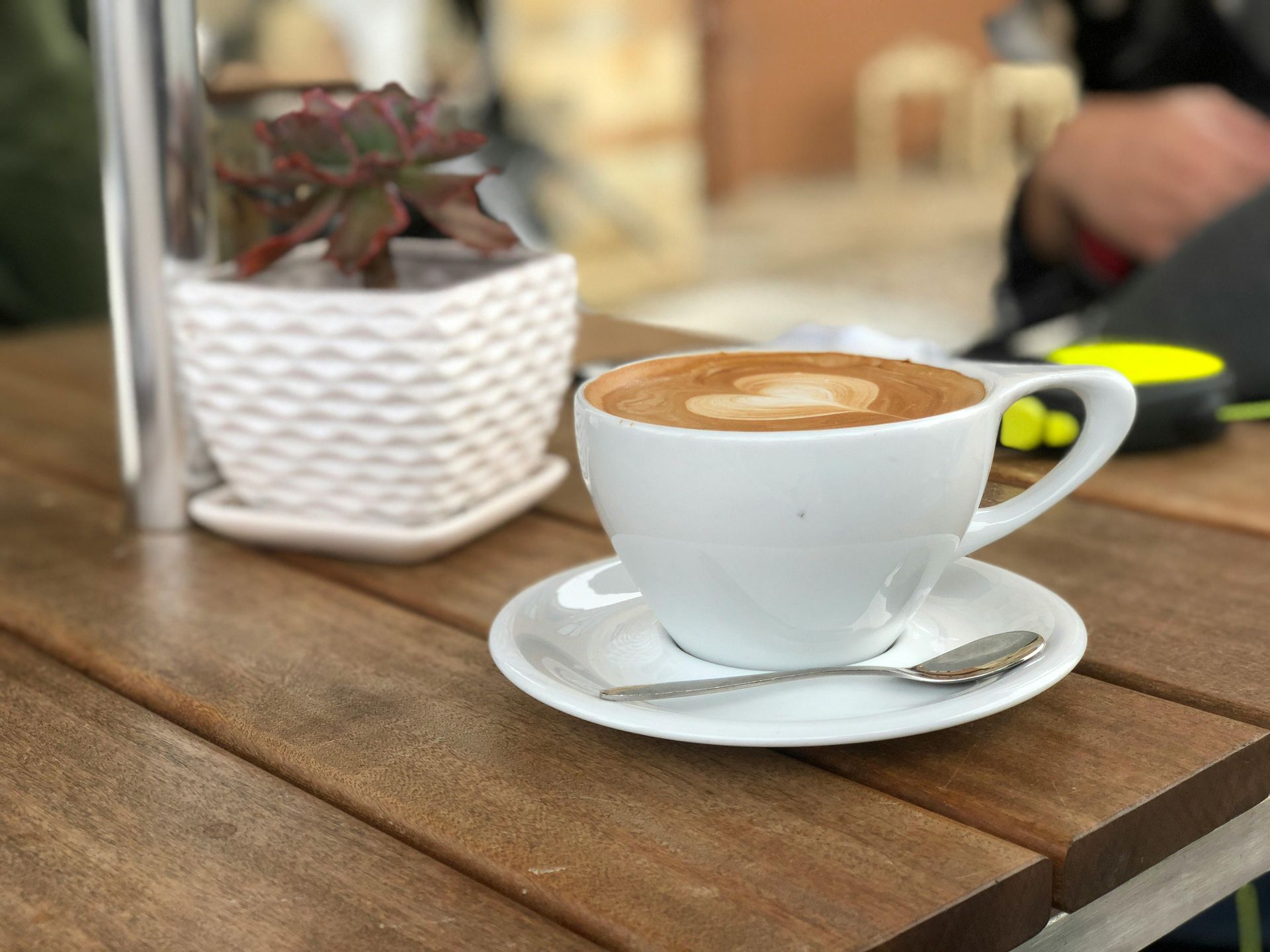 A cup of coffee on a saucer with a spoon on a wooden table.