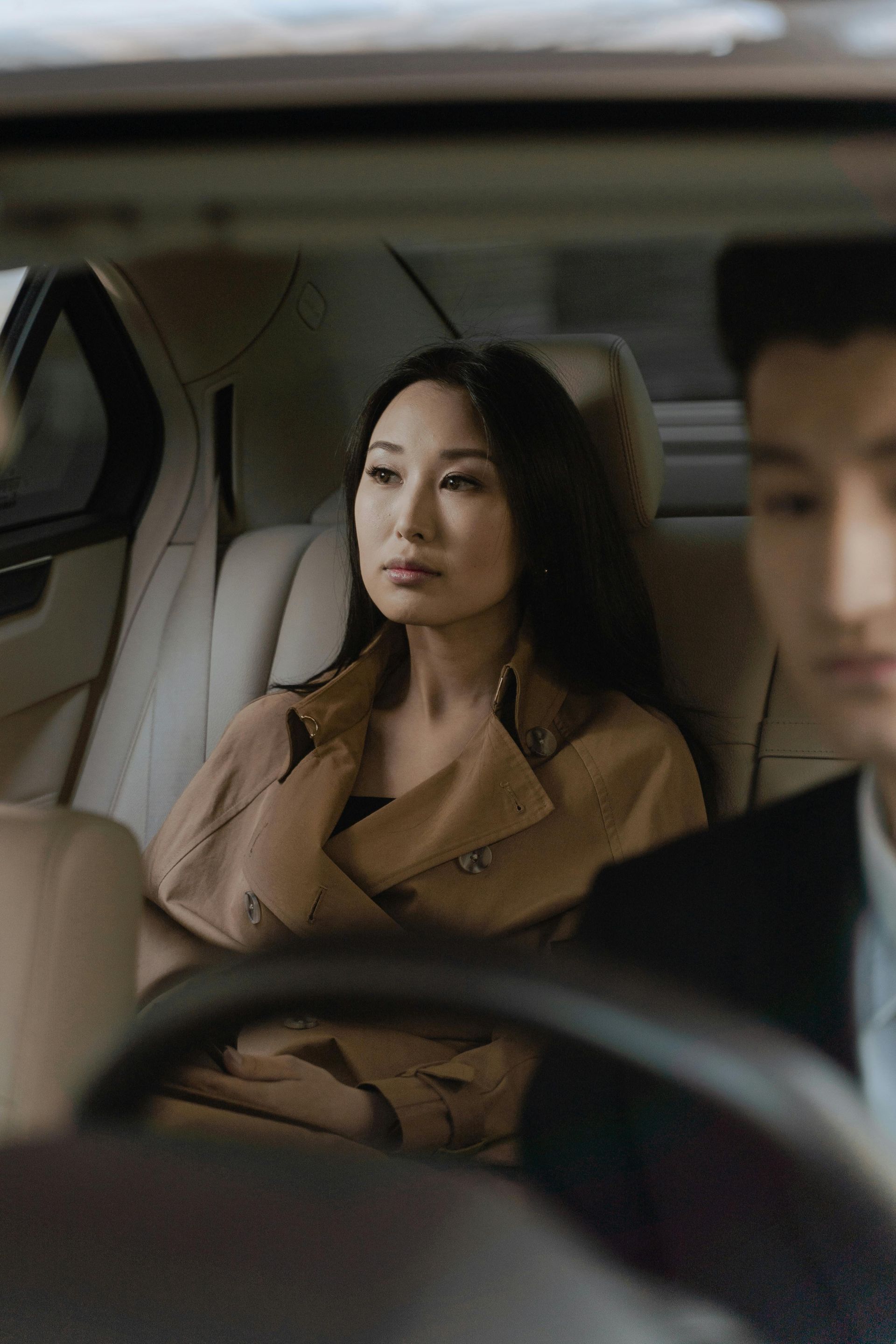 A man and a woman are sitting in the back seat of a car.