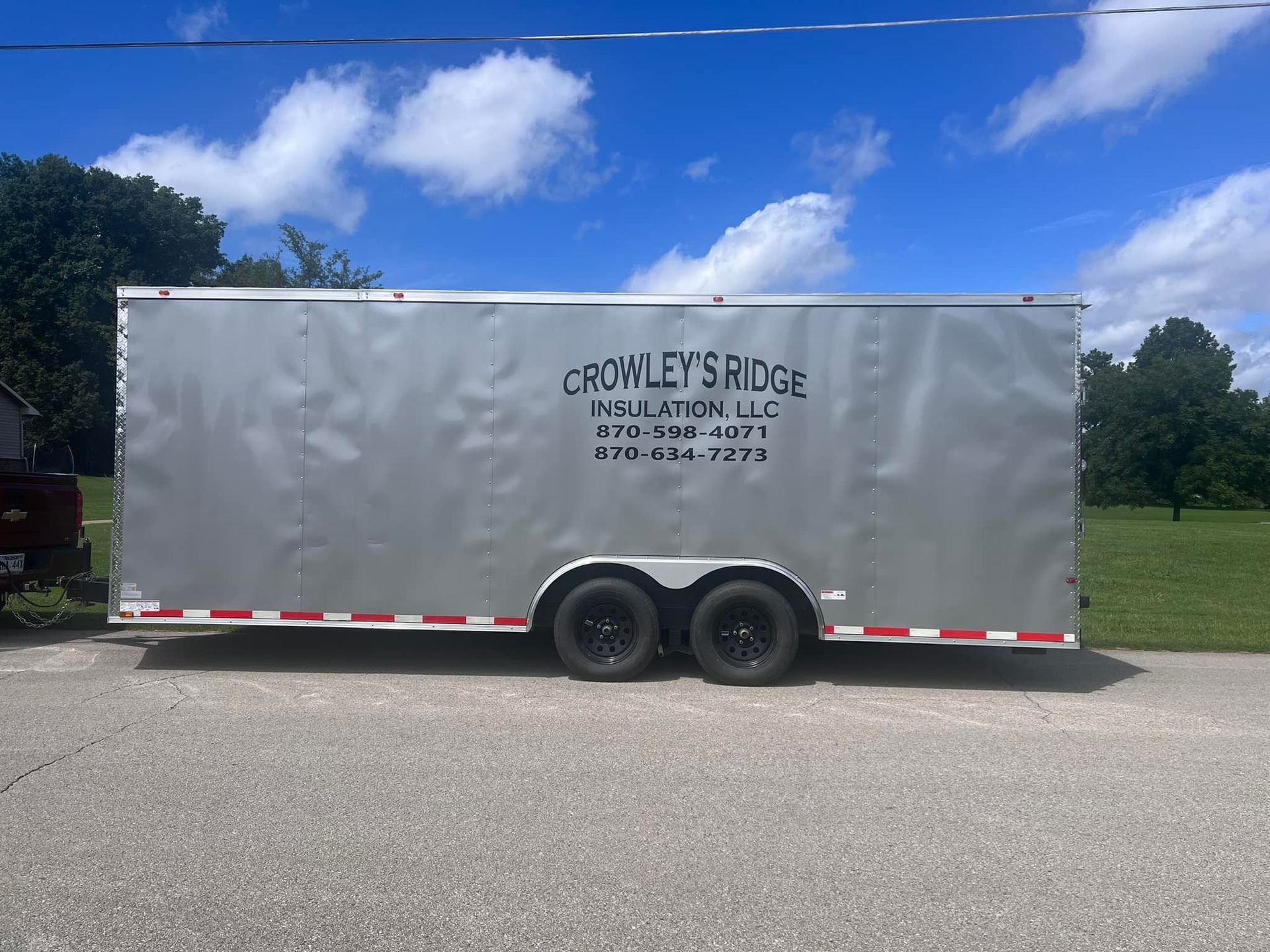 Silver enclosed trailer parked on a road, with 