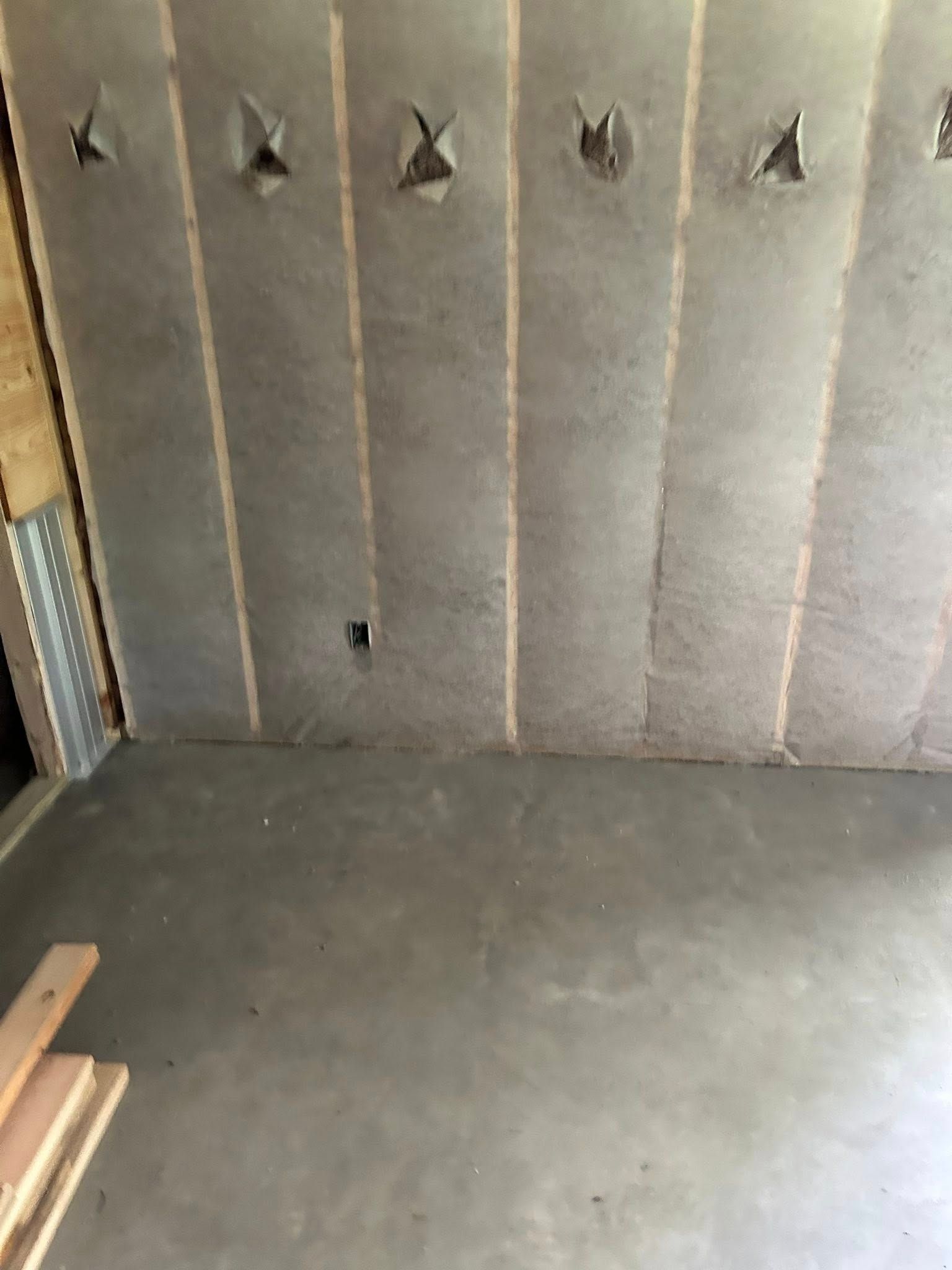 Concrete room with insulation on the wall. Wooden beams are on the floor.