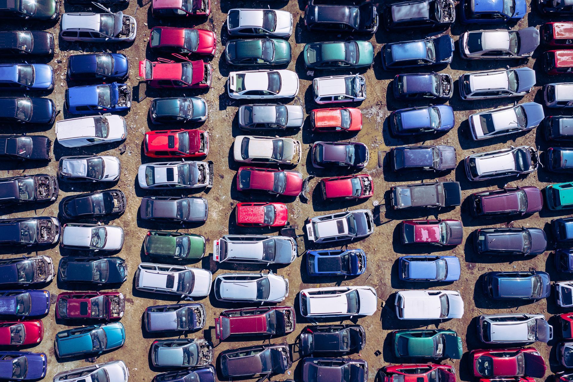 Aerial view of a vehicle salvage yard with rows of damaged and salvaged cars. Aerial view of a vehicle salvage yard with rows of damaged and salvaged cars.