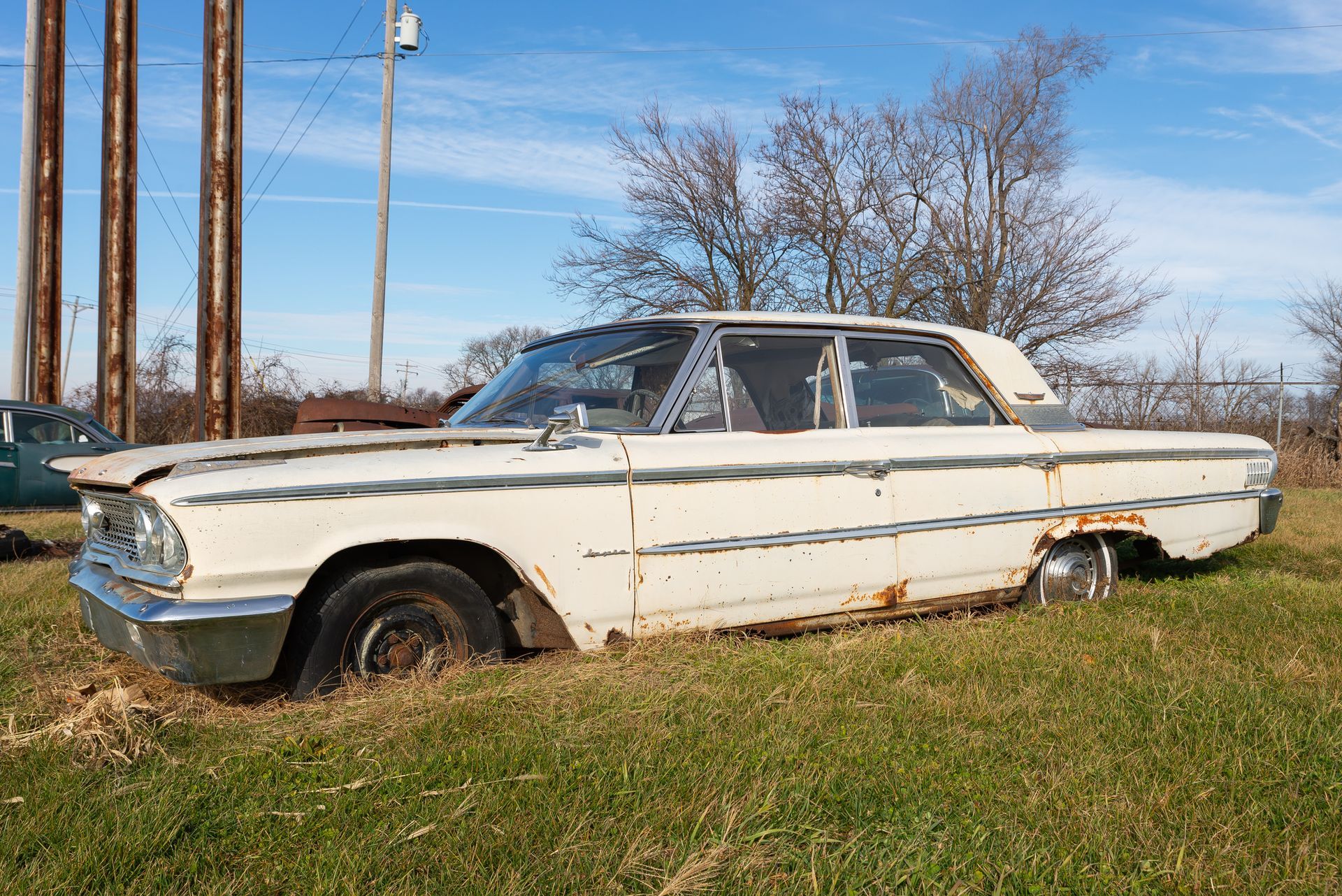 Classic car in a vehicle salvage yard waiting for restoration.