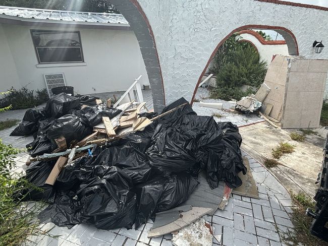 A pile of trash is sitting on the sidewalk in front of a house.