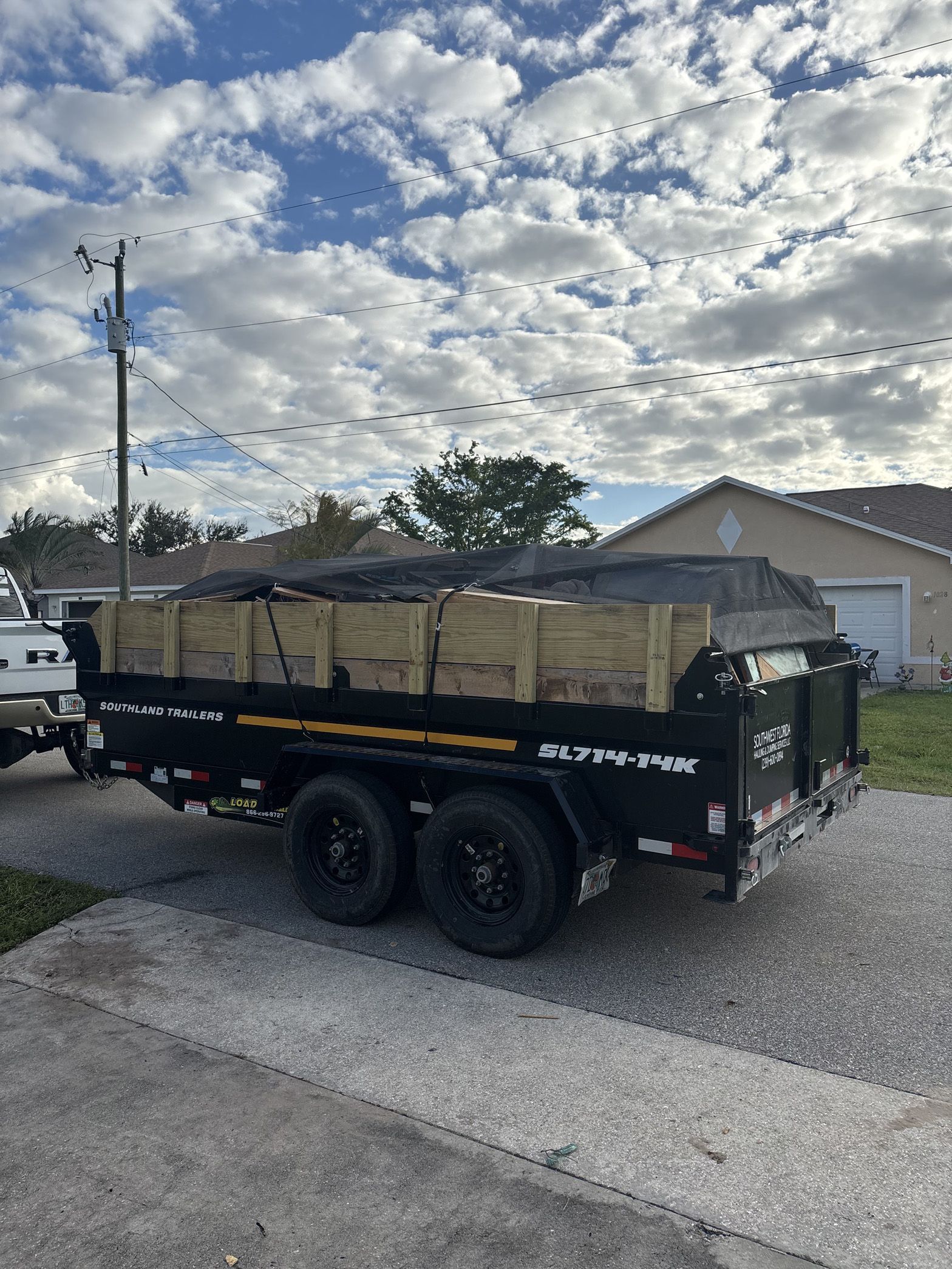 A dump truck is parked in a driveway next to a house.