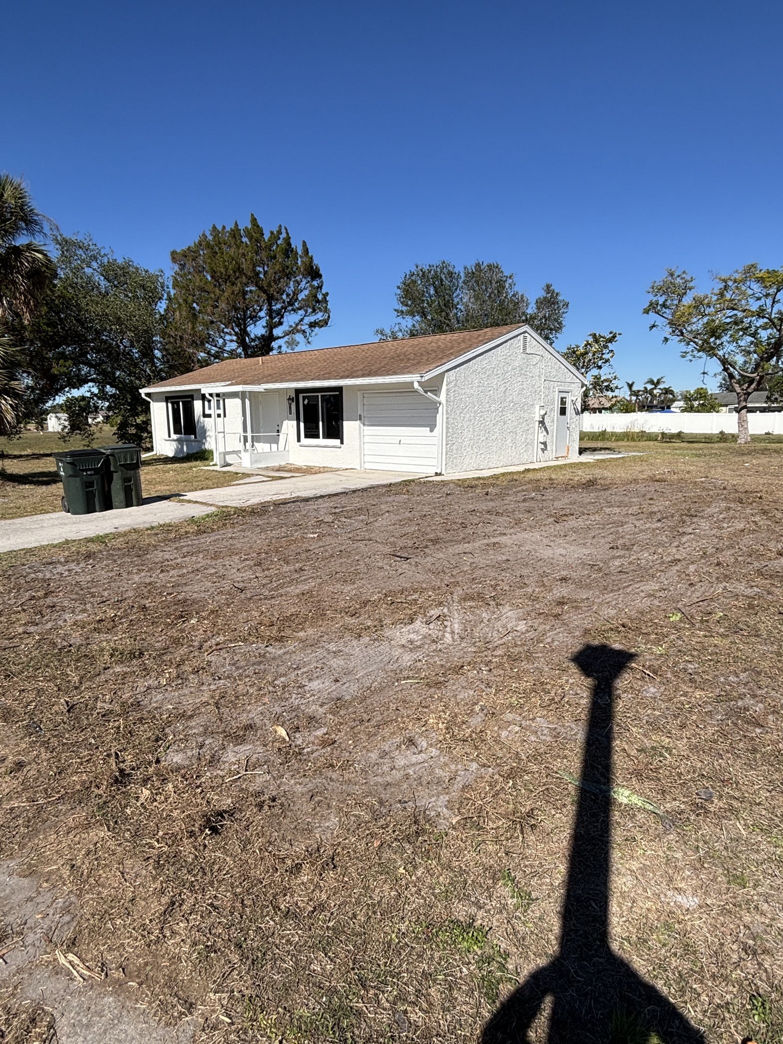 A shadow of a person is cast on the ground in front of a house.