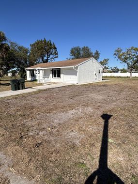 A shadow of a person is cast on the ground in front of a house.