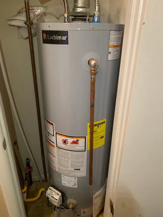 A water heater in a closet, with copper pipes and a gas line.