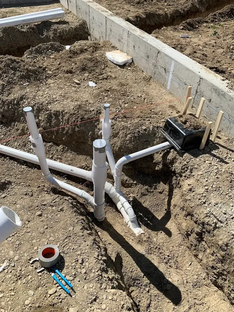 Plumbing pipes installed in a trench on a construction site.