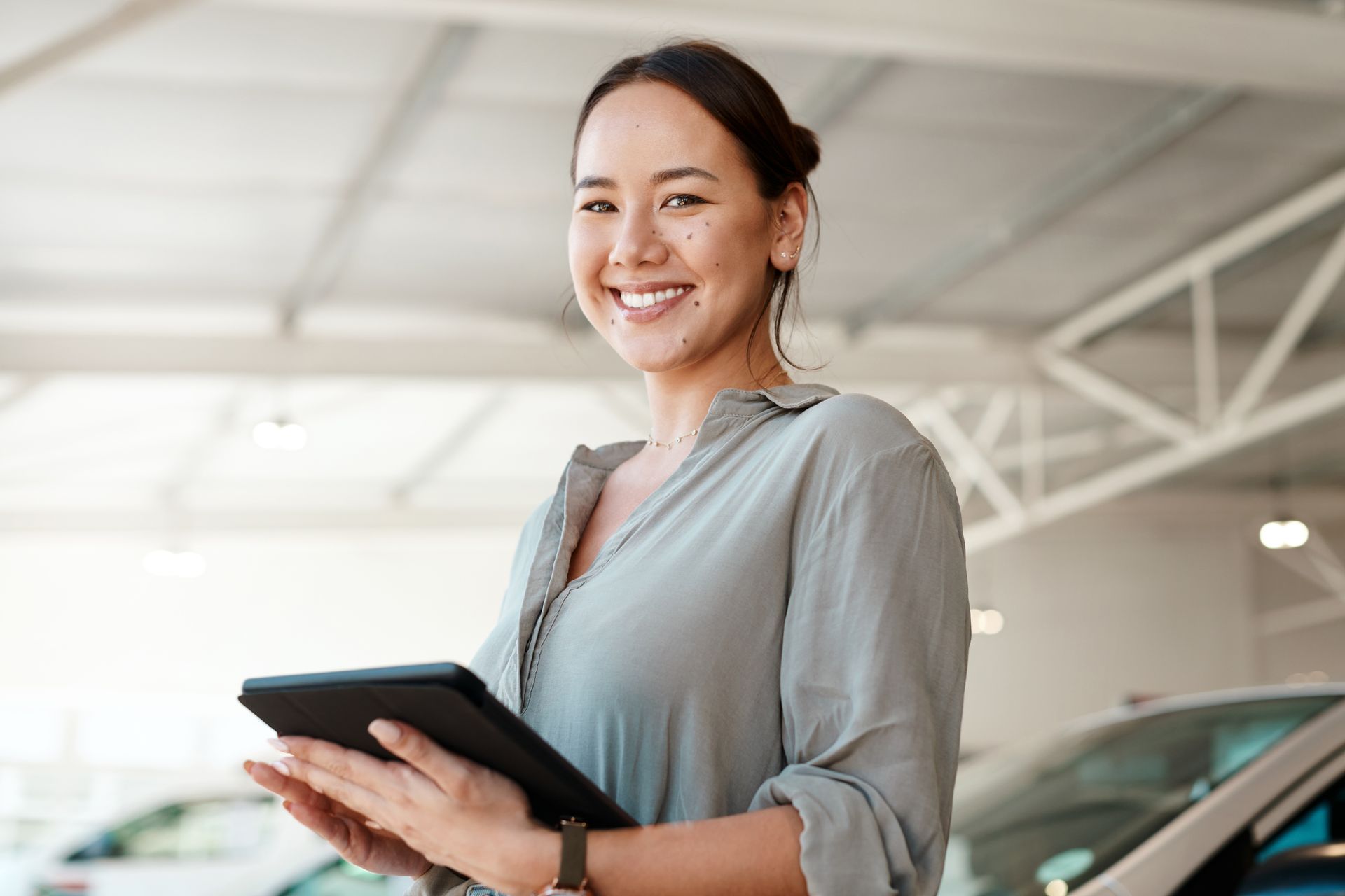 A smiling woman is holding a tablet.
