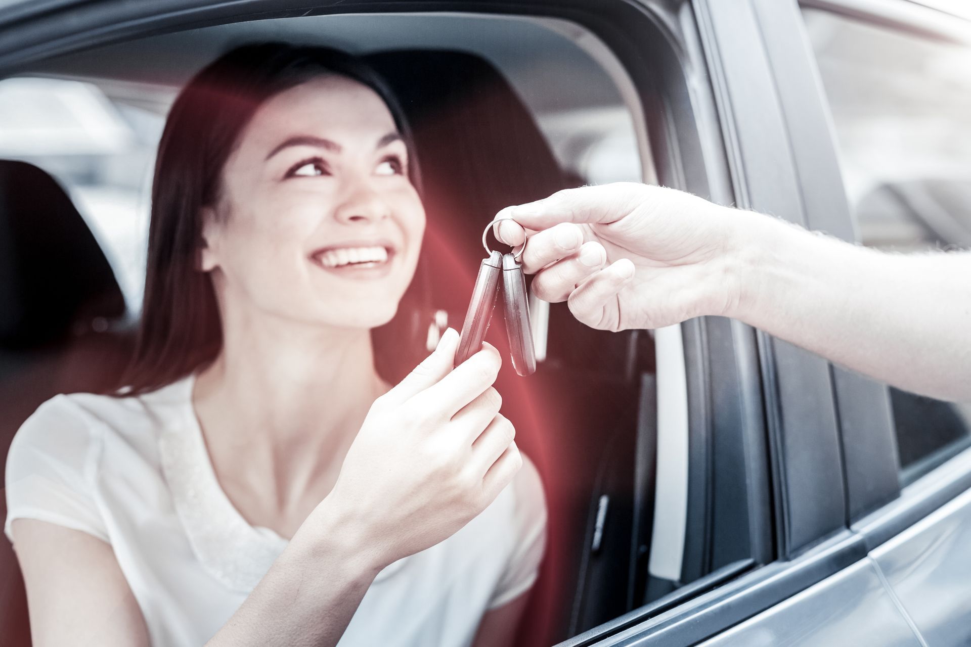 Extremely happy young lady grinning broadly while sitting in her automobile.