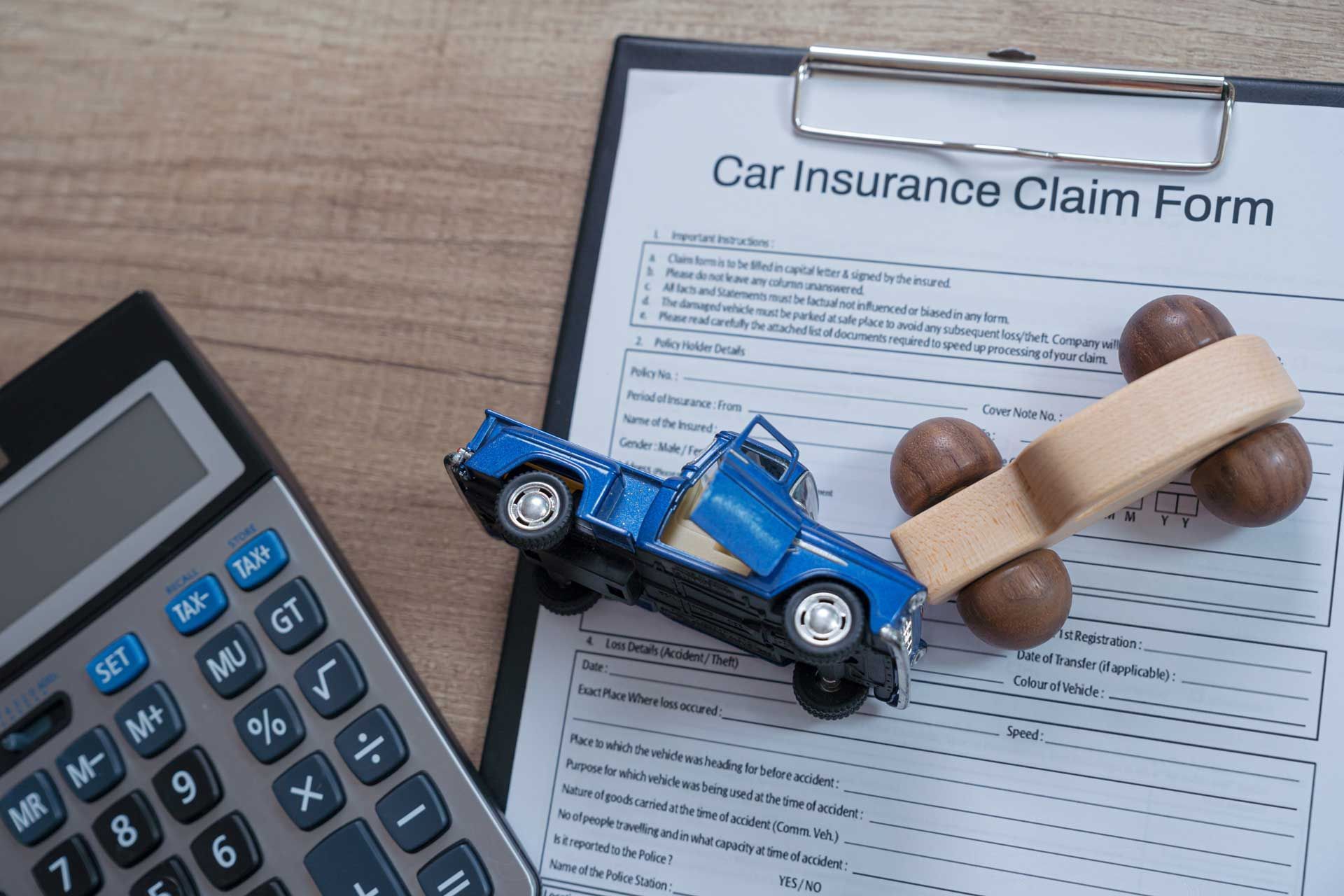 Car insurance claim form with toy car and calculator Omaha.