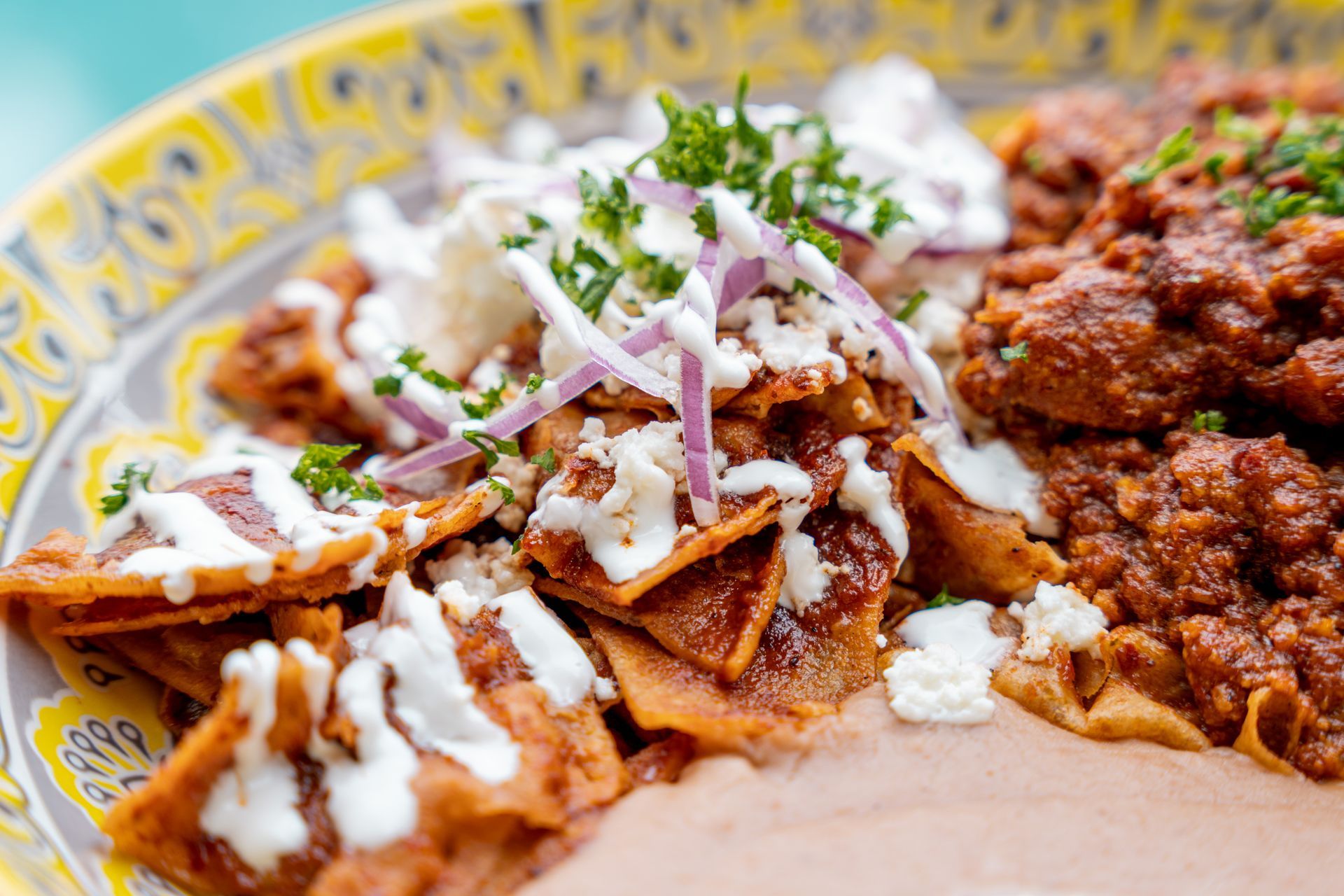 Plate of chilaquiles with toppings, and a side of meat.