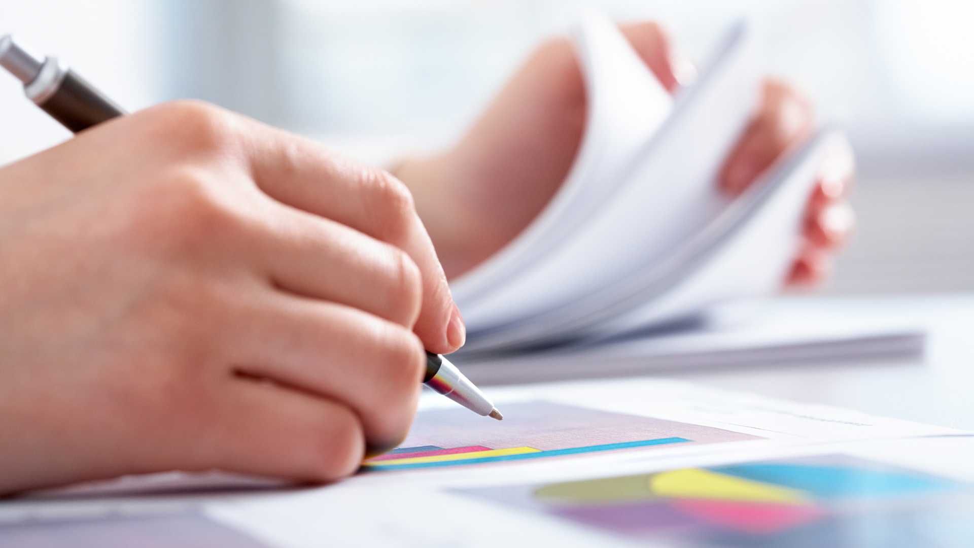 A person is writing on a piece of paper with a pen.