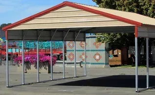 A carport with a red roof is sitting in a parking lot.