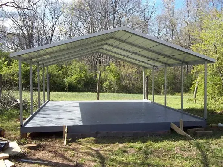 a carport is being built in a grassy area with trees in the background