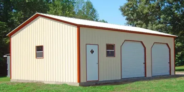 a metal garage with two garage doors and a door is sitting in the middle of a grassy field .