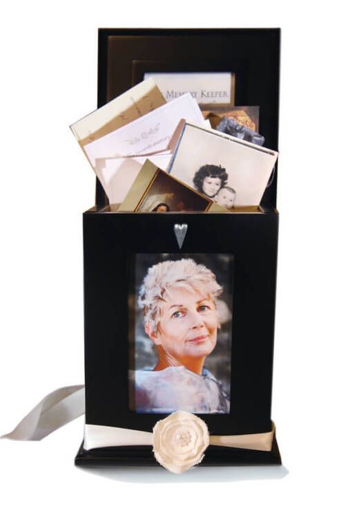 Black memorial box with photo of woman, holding cards and photos. Cream ribbon and flower detail.