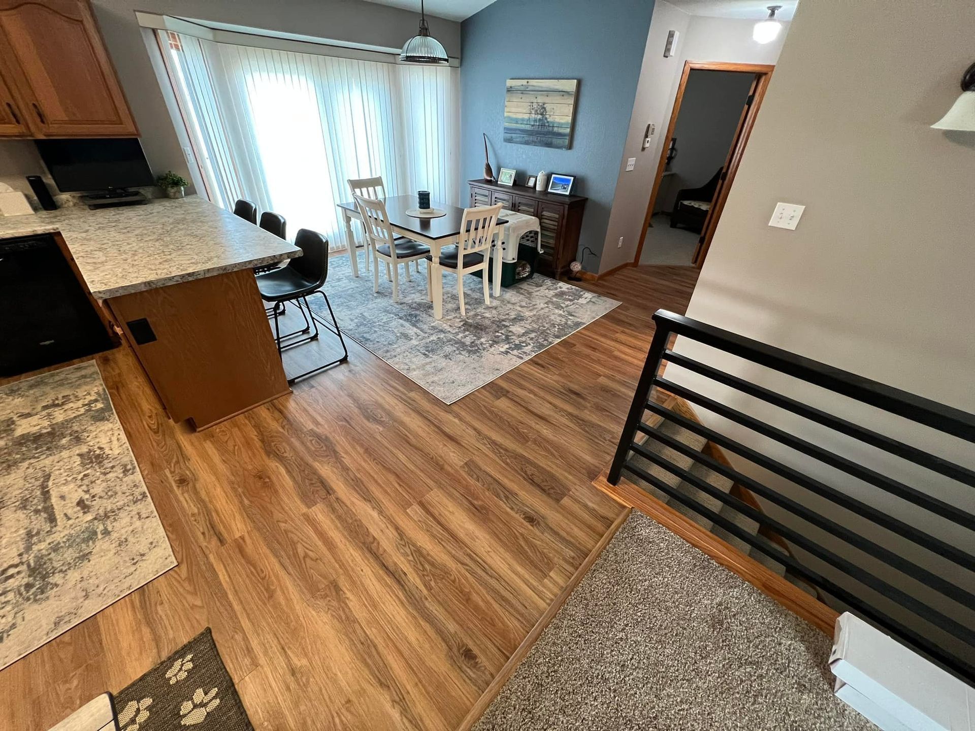Interior view of a kitchen and dining area with wood floors, a table, and a rug.