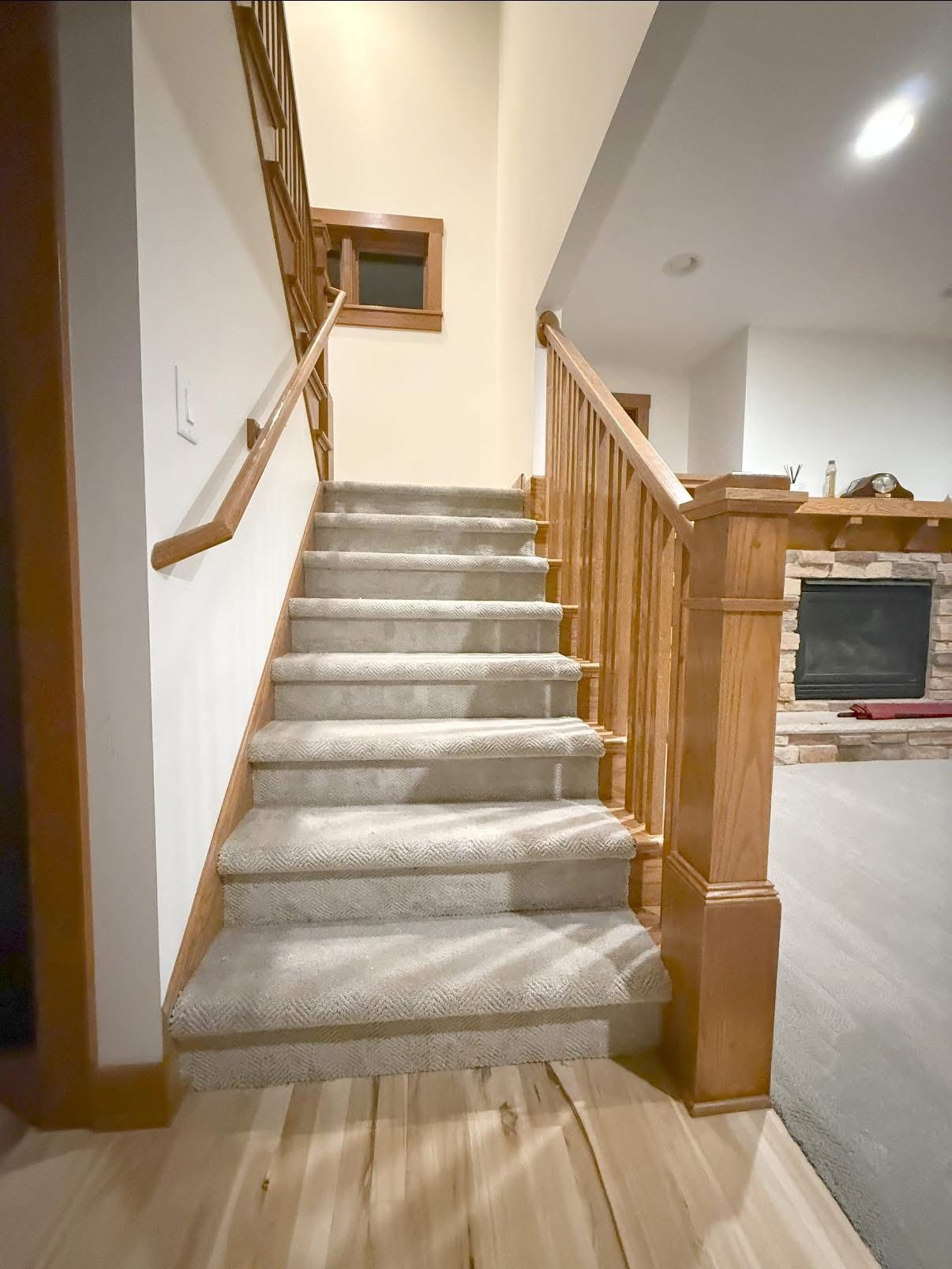 Staircase with carpeted steps and wooden railing leads upward; the setting is a house interior.