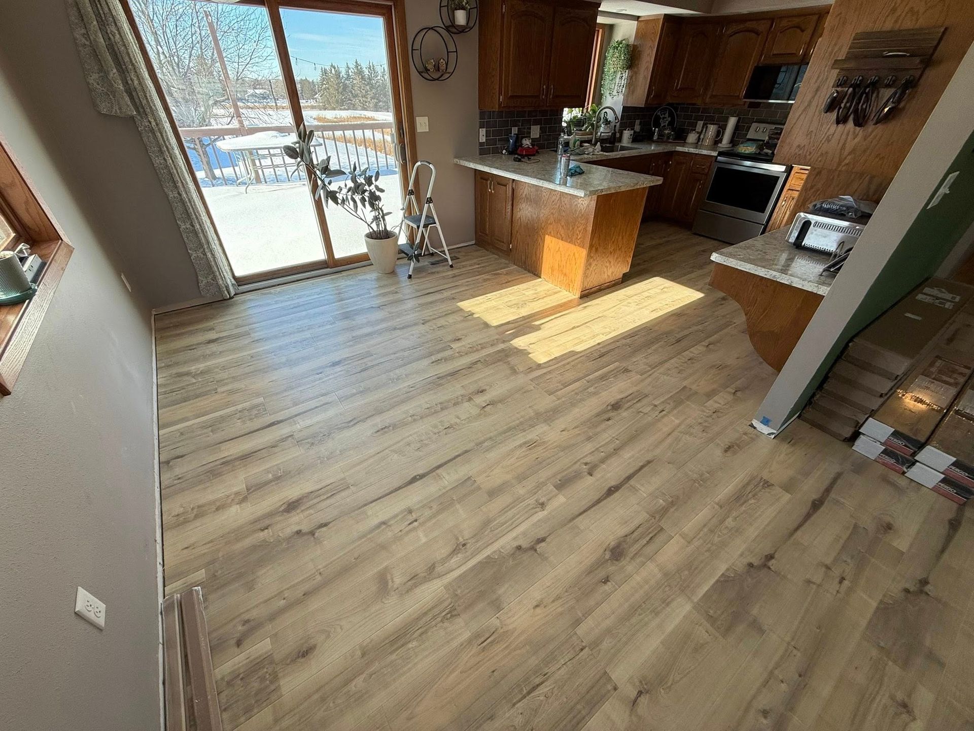 Light wood-look flooring in a kitchen with a sunny window and island.