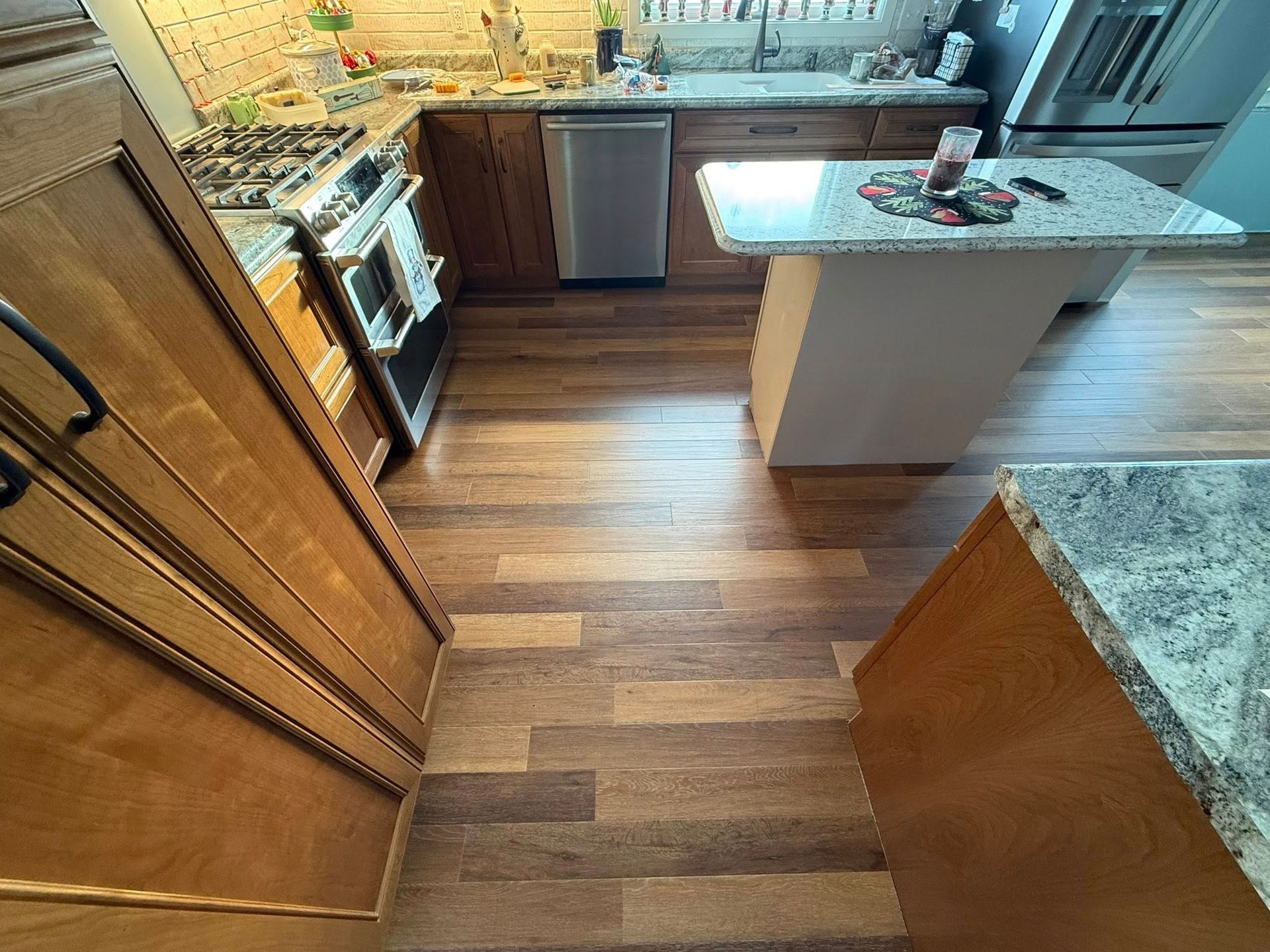 Kitchen with wood cabinets, stainless steel appliances, granite countertops, and wood floors.