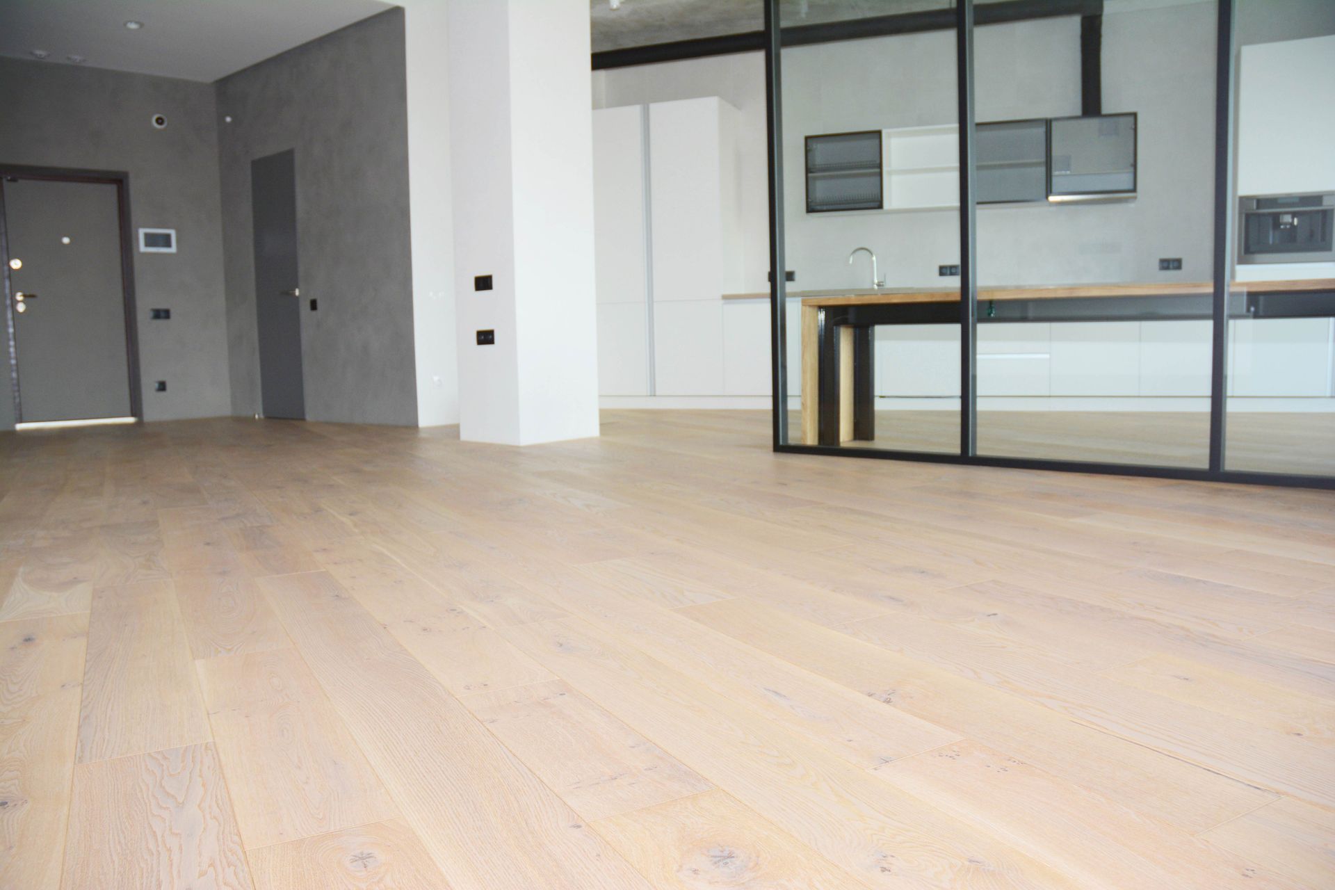 Empty living room with wood flooring, stone fireplace, and French doors.