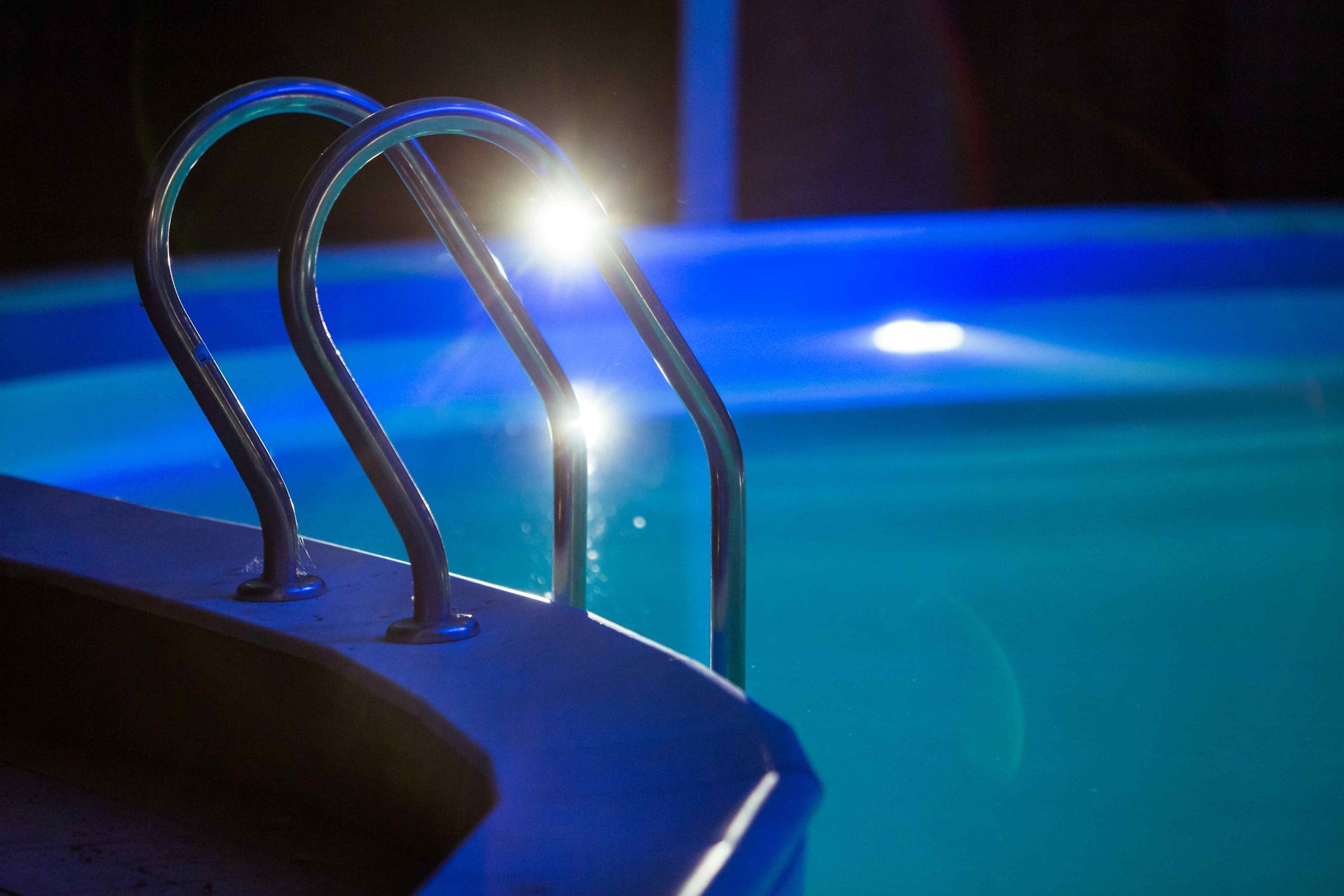 Image of pool at night with pool ladder in focus