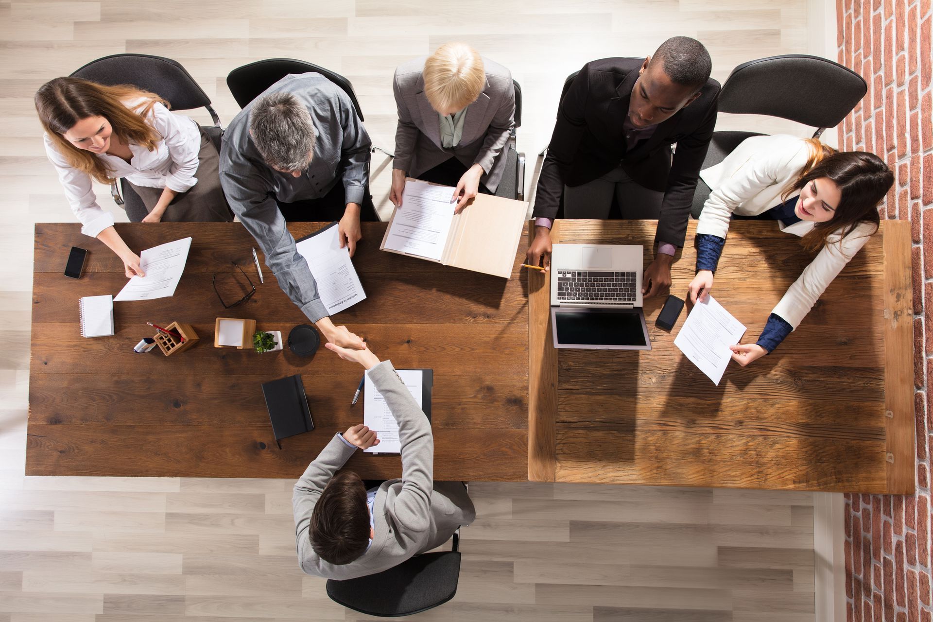 A group of people are sitting at a table shaking hands.