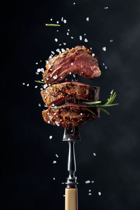 Un pezzo di bistecca è appoggiato su una forchetta.