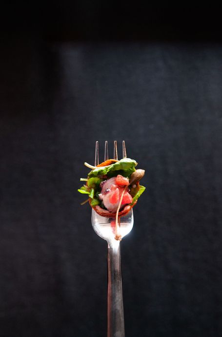 Una forchetta con un'insalata sopra su uno sfondo nero