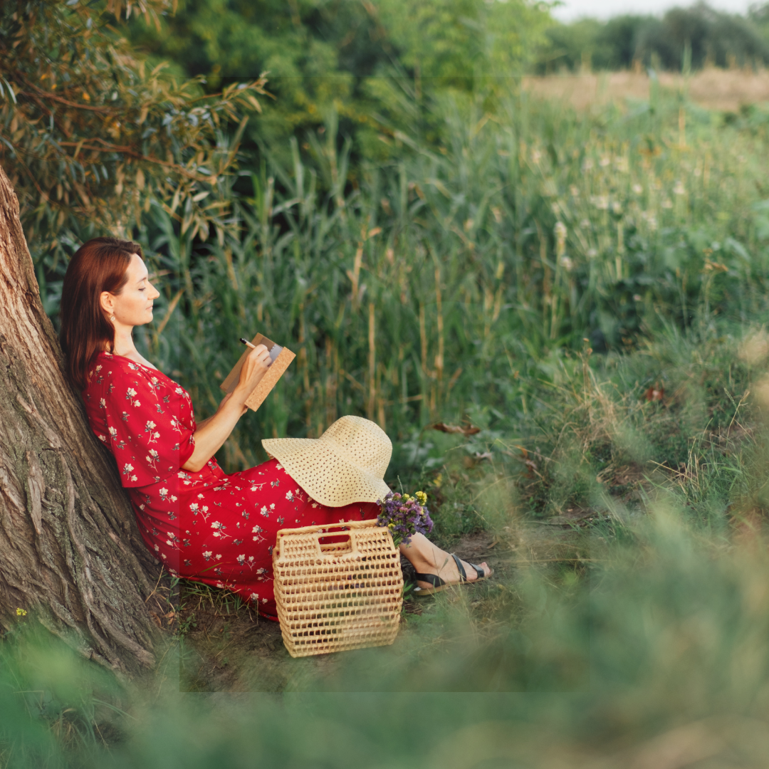 Woman sitting under a tree reading a book by herself and enjoying being alone.