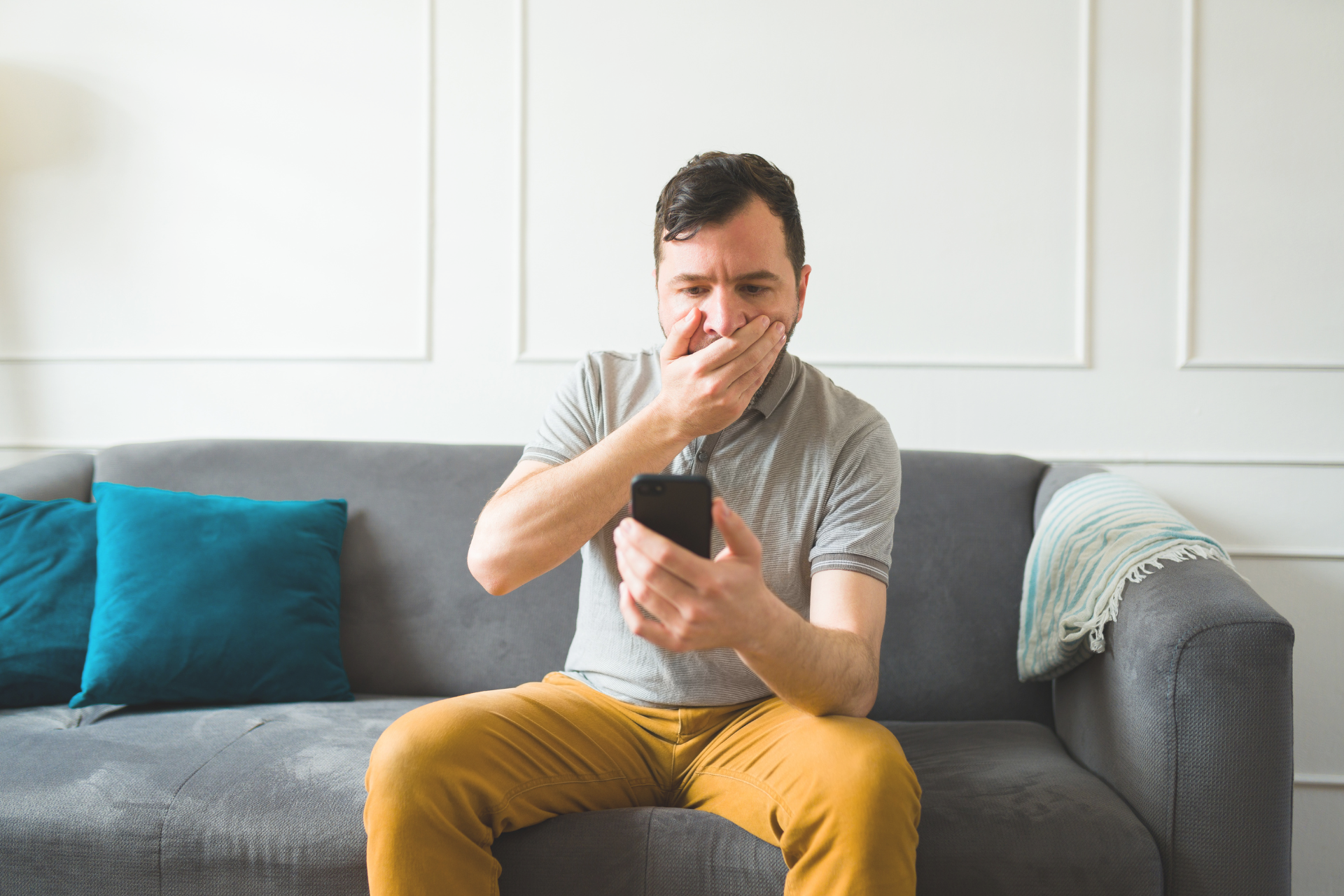 Man reading upsetting news on cell phone and is feeling very stressed and upset.