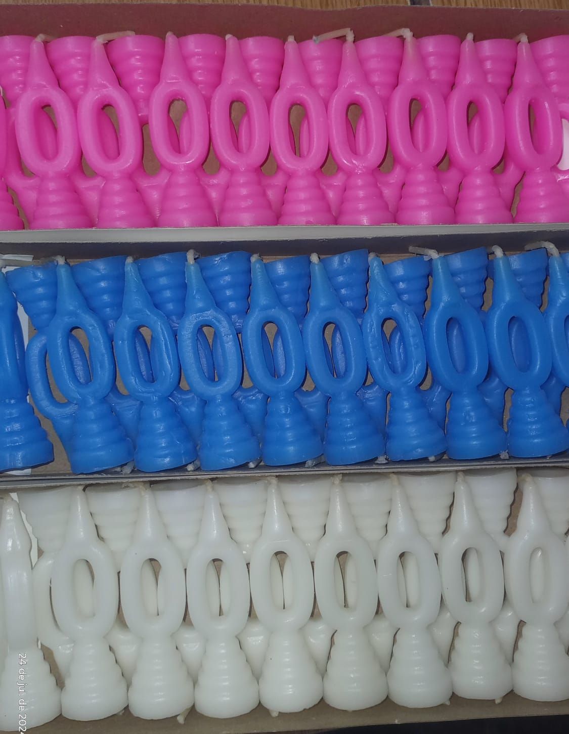 Filas de velas rosas, azules y blancas con diseño en forma de bucle.