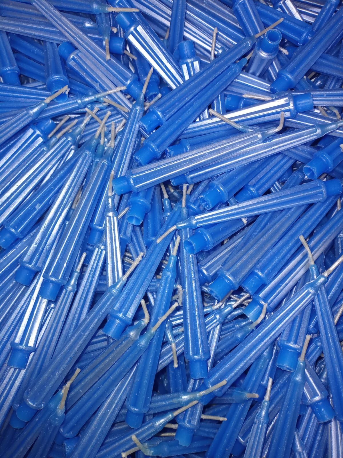 Pila de muchas velas cónicas azules con mechas visibles.