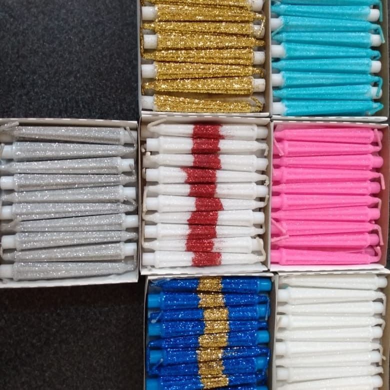 Nueve cajas de velas brillantes en varios colores, apiladas juntas.